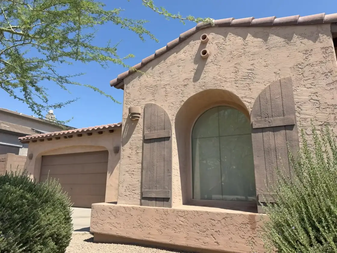 Freshly repainted Phoenix stucco home exterior with tile roof, wood shutters, and desert landscaping